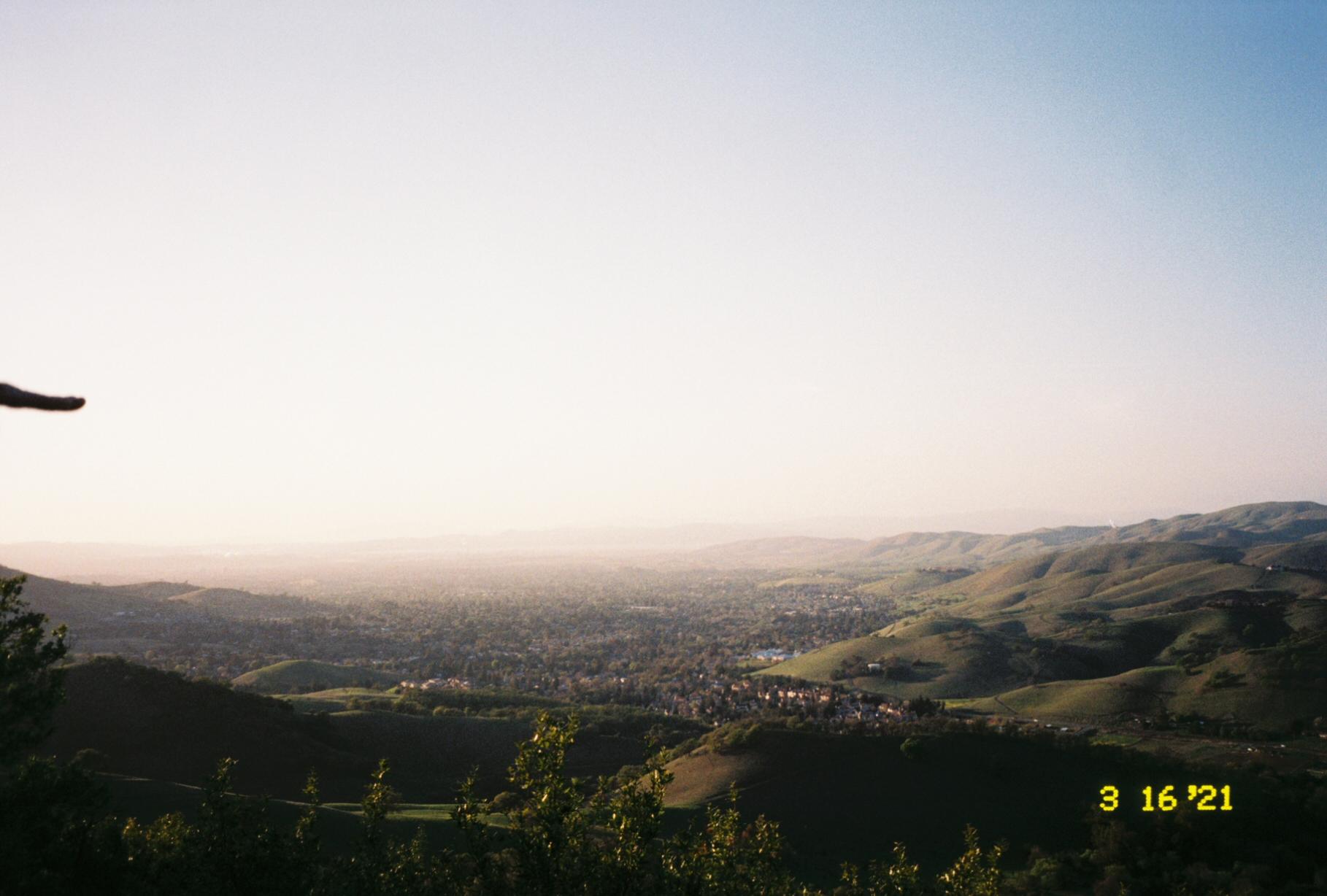 a green valley with a town in the center seen from a distance