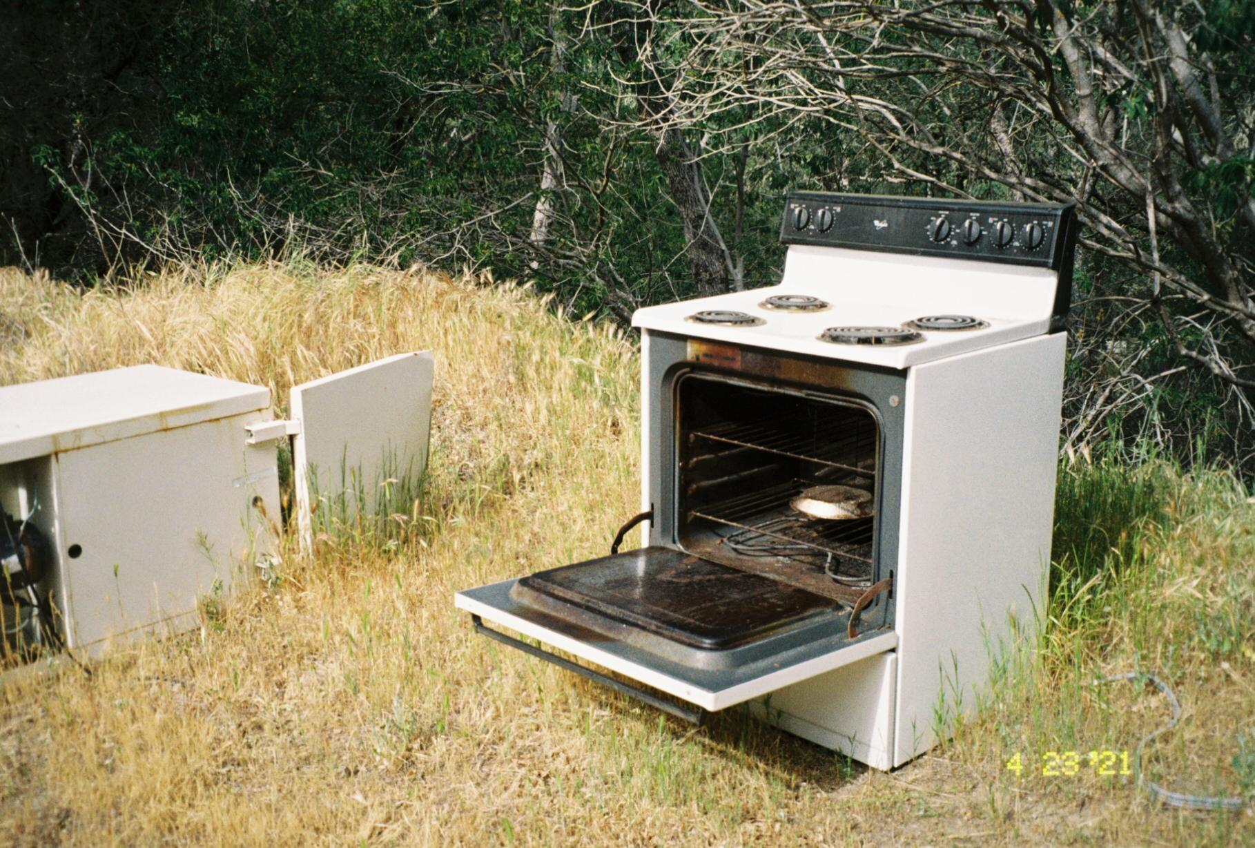 an open oven outside in dead brush
