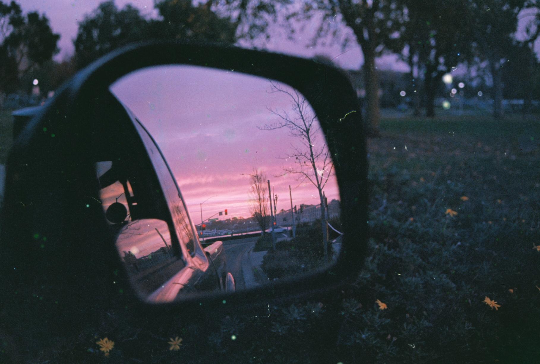 a pink sunset reflected in a car mirror