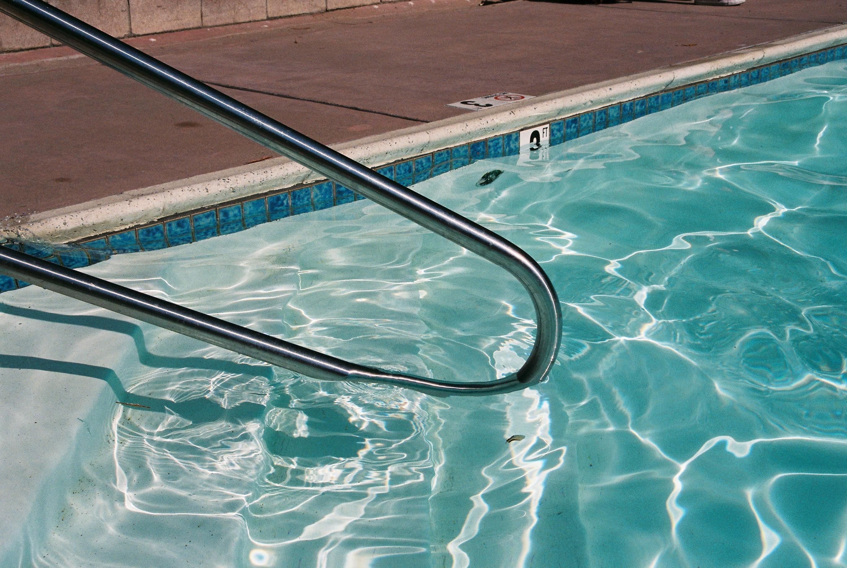 a metal railing partially submerged in a pool with light blue water