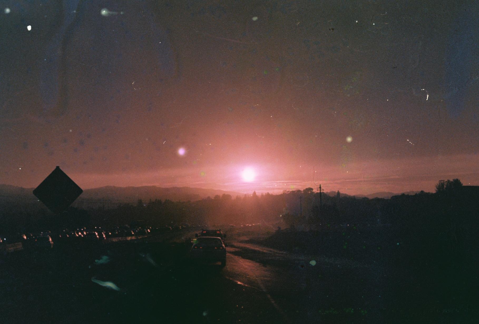 a pink sunset over a highway filled backed up with traffic