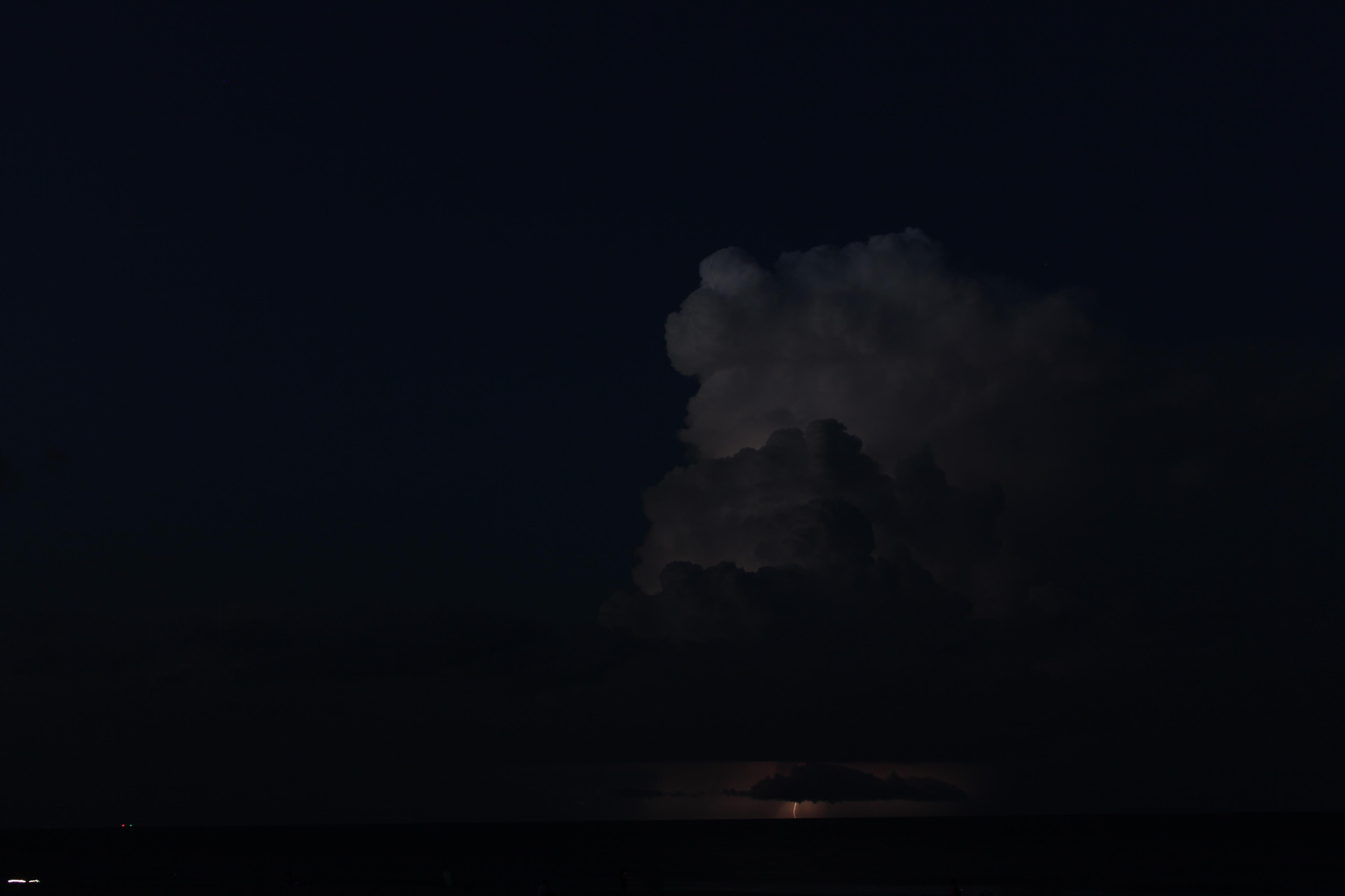 a large cloud with a small lightning strike below it