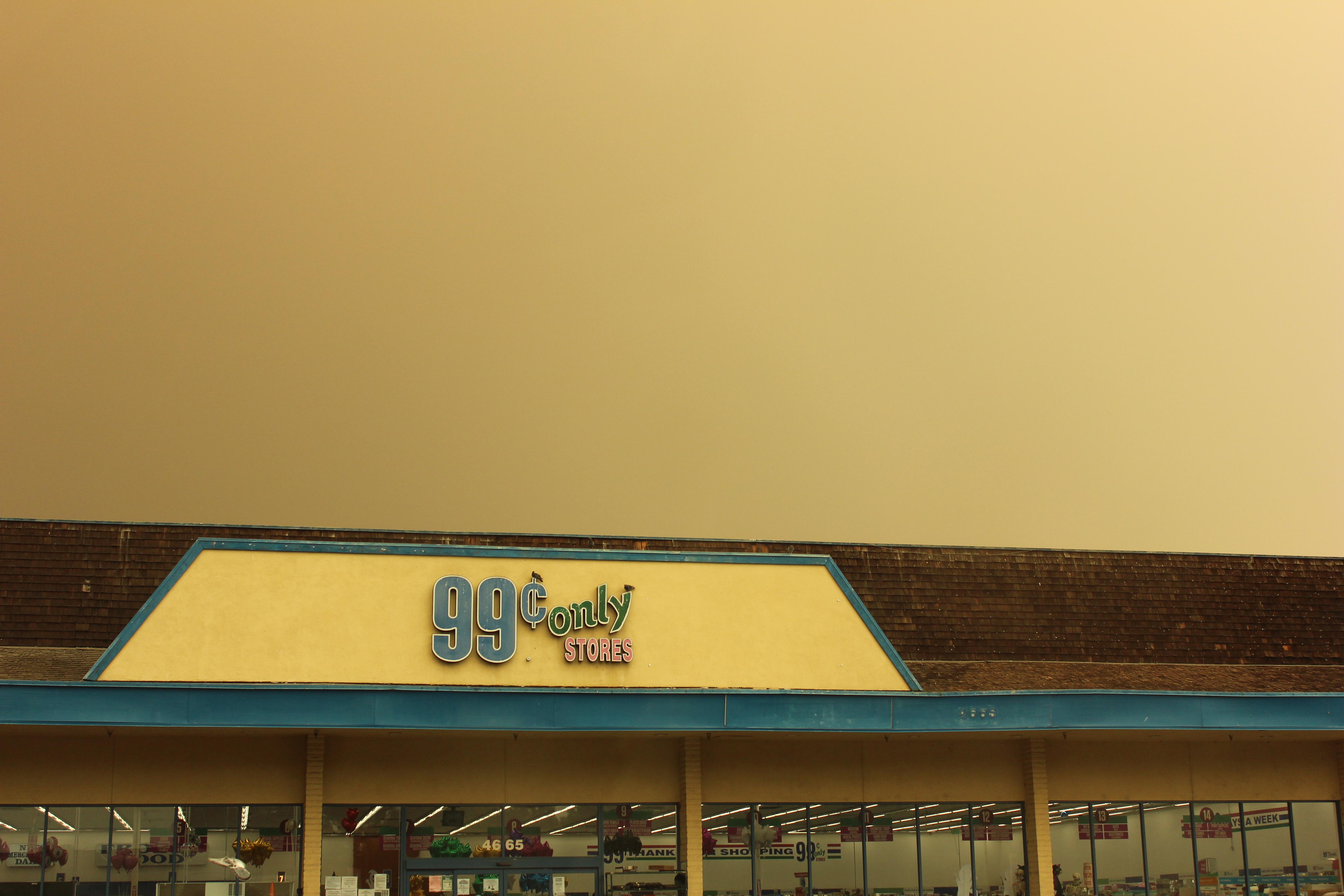 the roof of a 99 cent only store with a smog-filled sky behind it