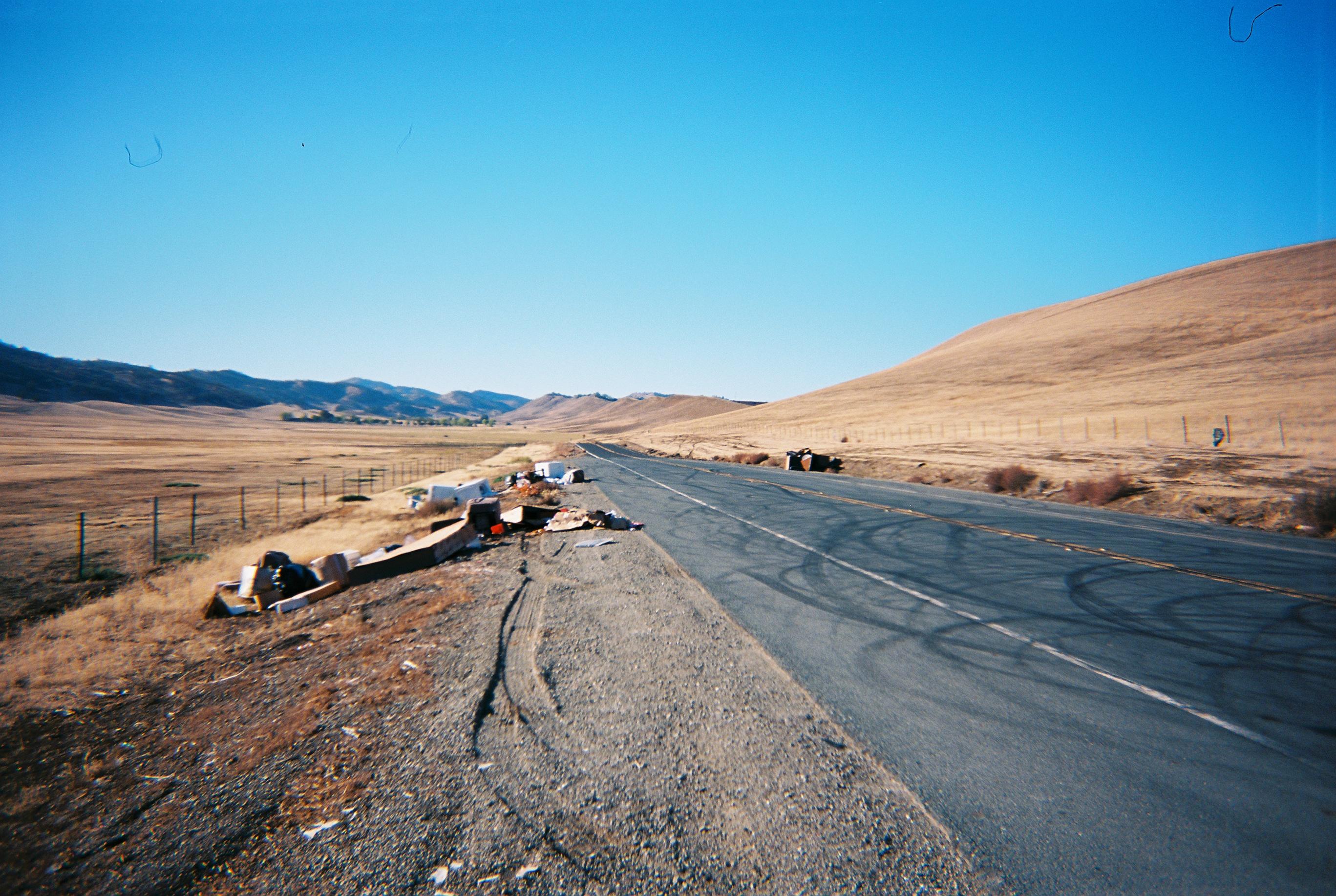 a road in a barren valley with garbage scattered on the sides