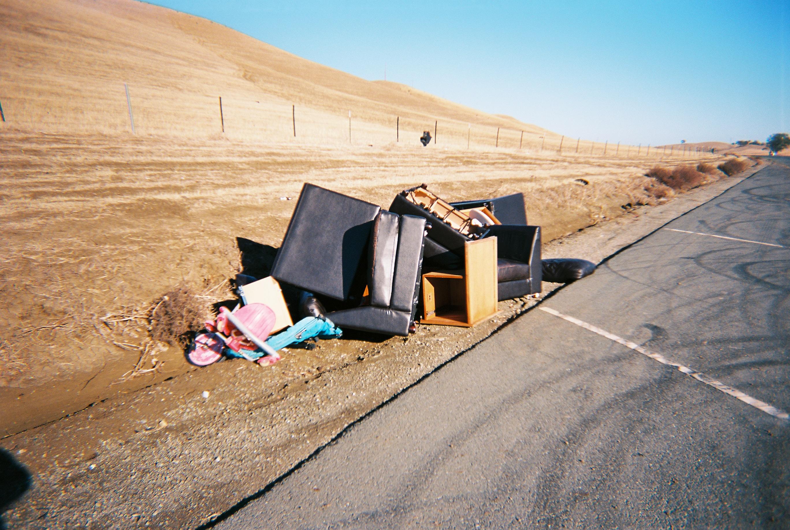 a pile of chairs and sectionals on the side of the road